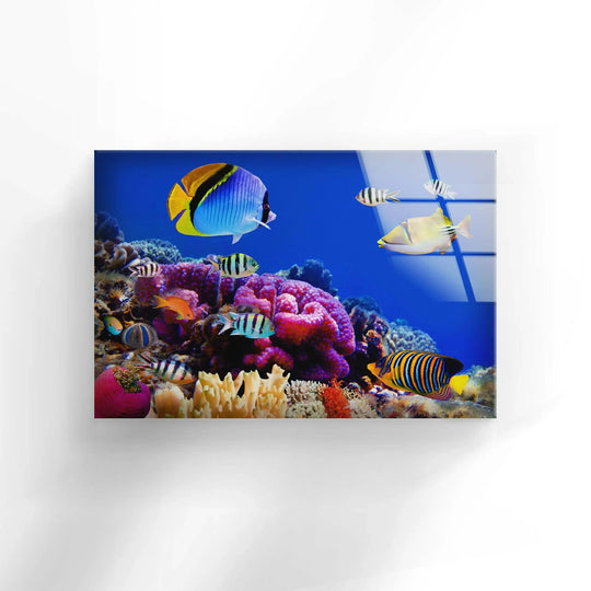 A vivid glass wall art decor features layers of colorful coral reefs teeming with diverse fish, creating a captivating underwater scene with a sense of depth.