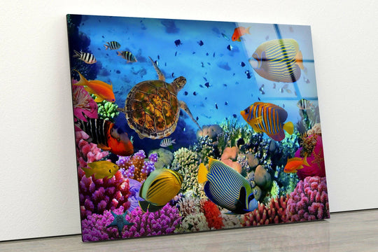 The organic forms of a sea turtle and colorful fish swim amongst vibrant coral in this glass wall art decor.