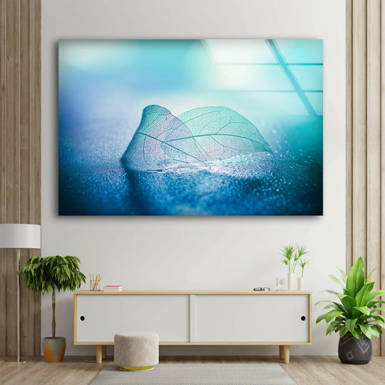 Blue skeleton leaf glass printing artwork displays a vibrant edge with a striking contrast between the cool blues of the leaf and the warm wood paneling border.