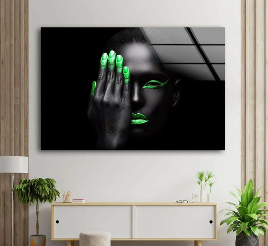 A woman's face, half-obscured by a hand with neon green nails, is dramatically lit against a dark background, creating striking contrasts in this decorative wall art.