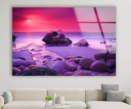 Foreground detail shows smooth, rounded rocks of the pink sunset beach wall art prints contrasting with the dreamy coastal landscape scene.