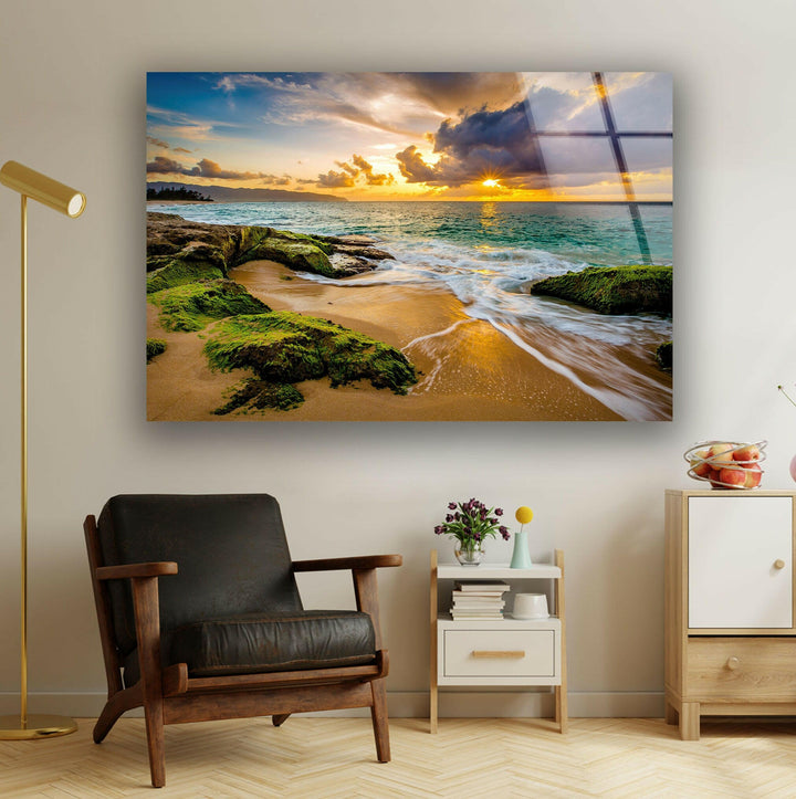 Coastal sunset wall art featuring a vibrant sky, crashing waves, and green mossy rocks.
