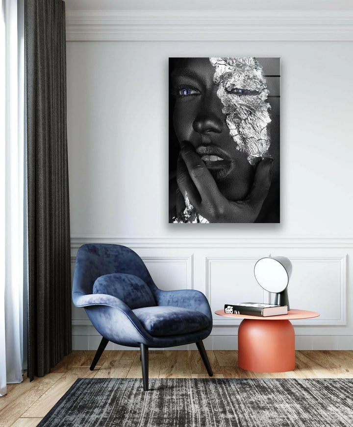 Dramatic grayscale artwork depicting a textured face with shimmering silver details and glowing blue eyes.