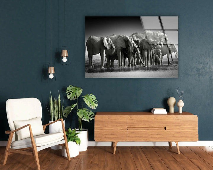 Monochrome glass artwork showing multiple elephants drinking together in a calm landscape.