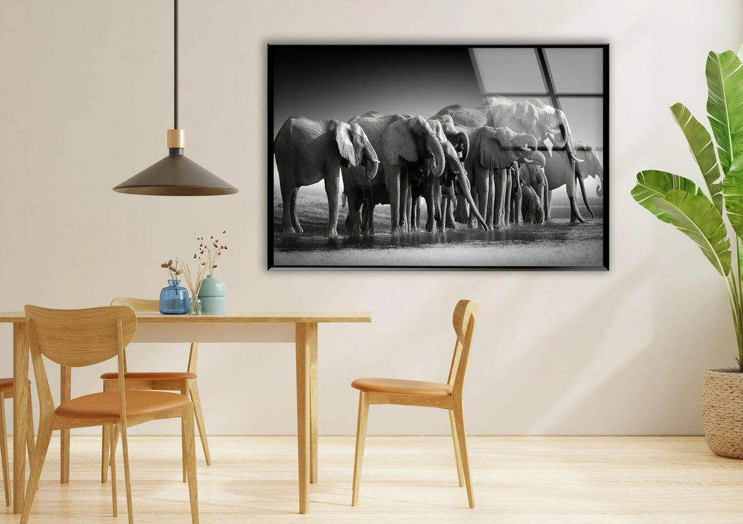 Detailed grayscale glass art of an elephant herd gathered in a peaceful outdoor environment.