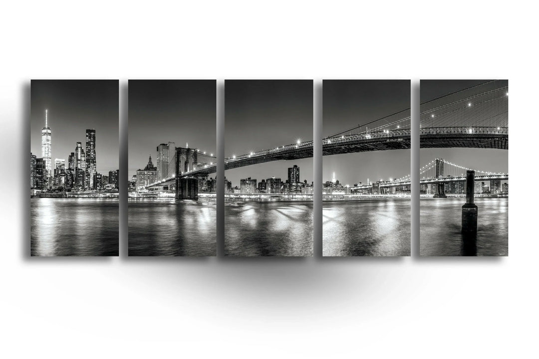 Panoramic black and white view of New York City lights and the Brooklyn Bridge.