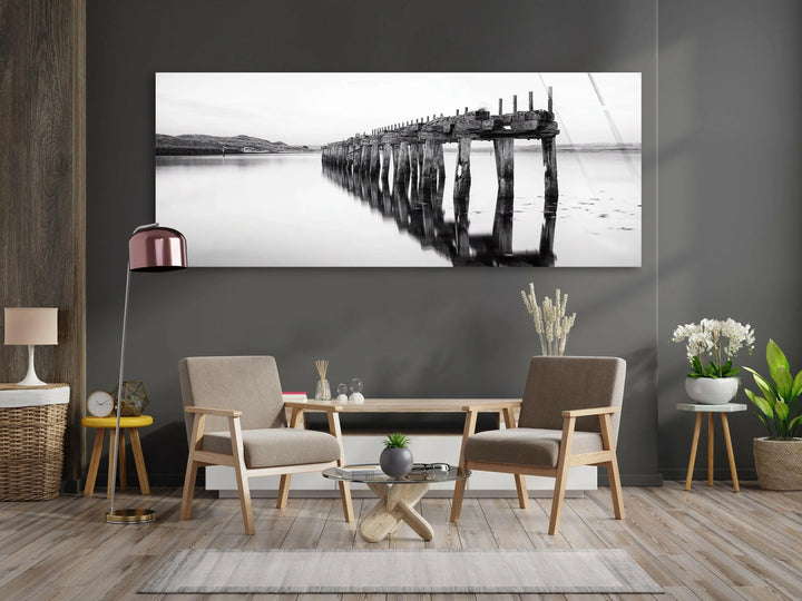 Serene black and white glass wall art featuring an old wooden pier reflected on calm water.