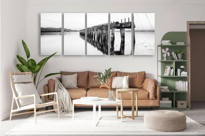 Peaceful glass wall art of a long rustic pier mirrored perfectly in smooth reflective water.